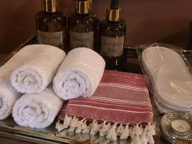 Masaj yağları, rulo havlular, kırmızı çizgili peştemal ve terlik — Esentepe, Masaj Salonun